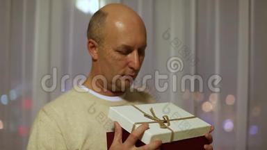 成人白种人男子打开礼品盒和惊喜。 一个惊喜的人看着盒子里的礼物